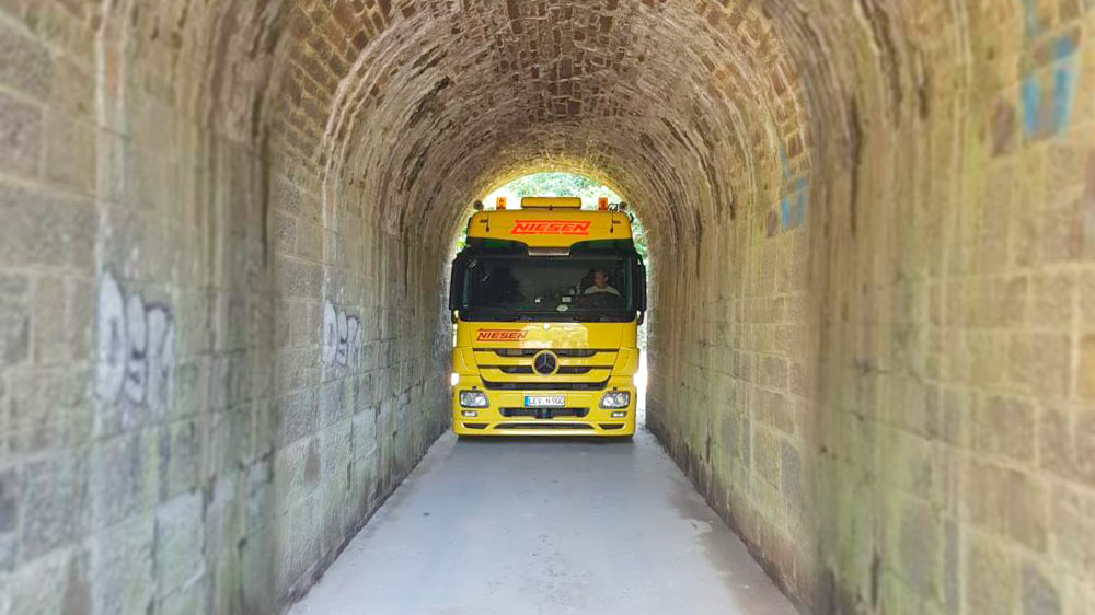Millimeterarbeit: Zwei Kräne und ein Stapler bringen Container durch schmalen Eisenbahntunnel