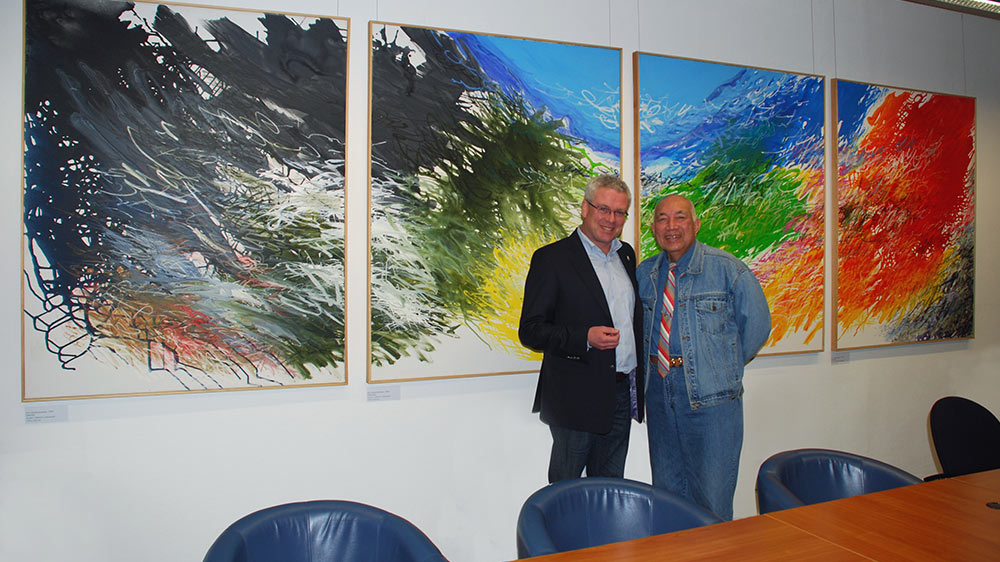 Klaus Niesen mit dem Künstler Boeldansjah Tirtawidjaja vor einem mehrteiligen Gemälde